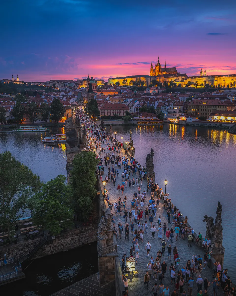 Karlův most za soumraku s Pražským hradem a katedrálou svatého Víta v pozadí.
